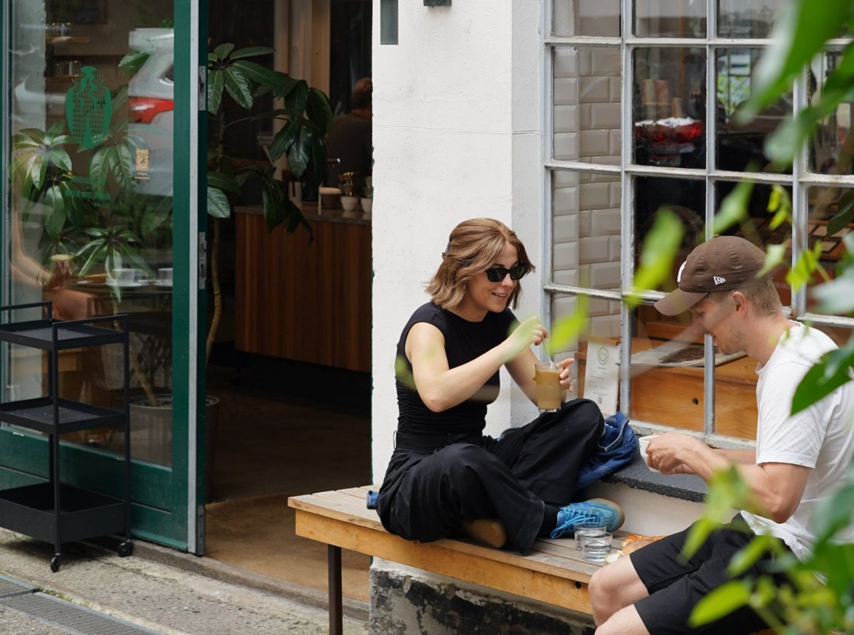 Two guests seated on a bench outside a SHOUT Media coffee shop